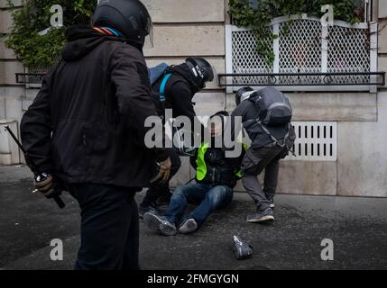 Des policiers sous couvert emprisonnent un manifestant près de l'Arc De Triomphe pendant le quatrième samedi des manifestations nationales par le movem des « gilets jaunes » Banque D'Images