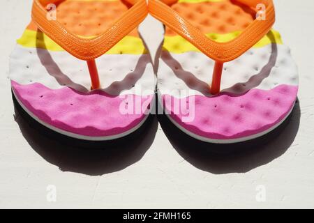 Tongs de plage colorées sur une table blanche. Banque D'Images