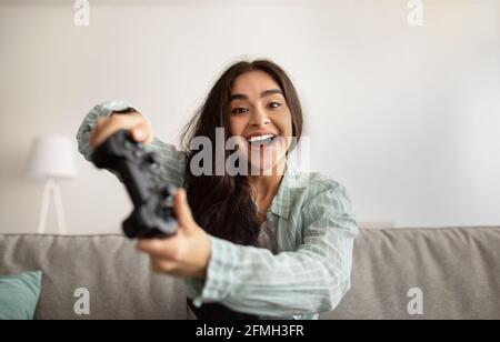 Une femme indienne joyeuse qui profite du jeu vidéo sur PlayStation, s'amuser à l'intérieur. Restez à la maison passe-temps et activités Banque D'Images