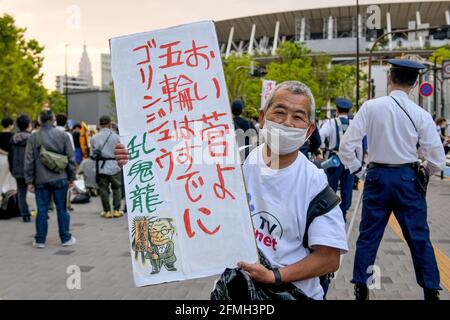 Tokyo, Japon. 09e mai 2021. Un manifestant tient un écriteau qui se lit « Hey M. le premier ministre Suga! Les Jeux Olympiques sont déjà morts" lors d'une manifestation contre les Jeux Olympiques de Tokyo devant le nouveau stade national, le principal stade des Jeux Olympiques de Tokyo. Il reste moins de 3 mois jusqu'à l'ouverture des Jeux Olympiques de Tokyo en 2020, et le Japon continue de s'inquiéter de la possibilité d'accueillir un événement aussi énorme pendant la pandémie COVID-19 en cours. Crédit : SOPA Images Limited/Alamy Live News Banque D'Images