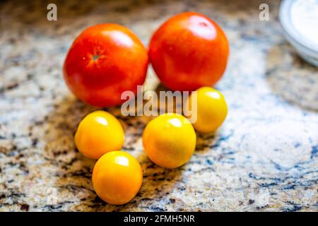 Gros plan sur les tomates maison orange et rouge fraîches du jardin après la récolte avec différentes variétés sur comptoir en granit dans la cuisine Banque D'Images