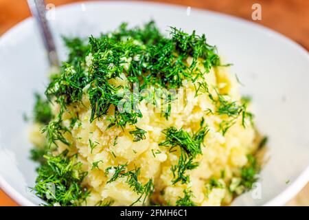 Gros plan du repas du soir légumes de purée de pommes de terre faites maison jaunes avec ail et aneth vert dans bol blanc macro avec texture Banque D'Images