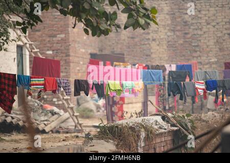 (Mise au point sélective) certains vêtements colorés lavés sont suspendus sur une ligne de vêtements ou de lavage sur le toit d'un bâtiment à New Delhi, en Inde. Banque D'Images