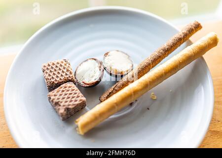 Assortiment d'en-cas de boule de truffe à la crème gastronomique, de biscuits au chocolat et de biscuits sucrés roulés avec garniture sur plaque blanche macro-gros plan Banque D'Images
