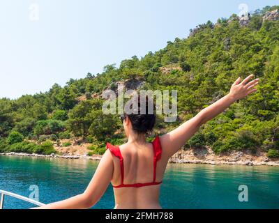 Vue de l'arrière de la magnifique femme en forme de cheveux sur la terrasse du bateau. Concept d'été avec fond vert nature Marmaris, Turquie Banque D'Images