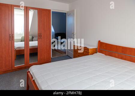 Intérieur confortable de la chambre avec grand lit double recouvert d'un protège-matelas blanc. Banque D'Images