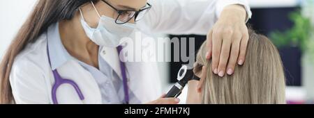 Otorhinolaryngologiste examinant les patients endoloris avec otoscope en clinique Banque D'Images