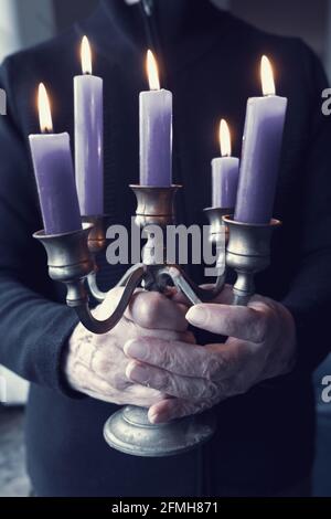 gros plan des mains de femmes plus âgées tenant le candélabre avec des bougies bleues Banque D'Images