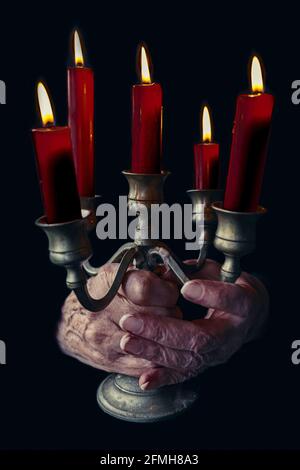 gros plan des mains de femmes âgées tenant le candélabre avec des bougies rouges Banque D'Images