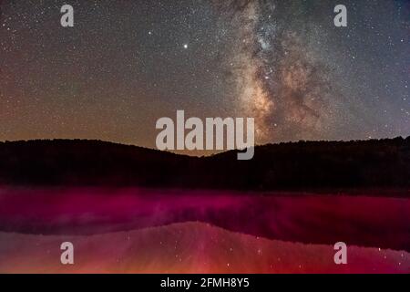 Ciel sombre de nuit avec galaxie laiteuse dans Spruce Knob Lac en Virginie occidentale avec reflet d'eau de couleur rose rouge de la lampe de poche sur le brouillard de brume monte stea Banque D'Images