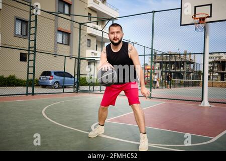 L'homme joue au basket-ball sur le terrain extérieur Banque D'Images