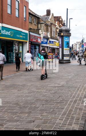 Compagnie de livraison de nourriture partenaire de Deliveroo à cheval électrique ou e-scooter sur la zone piétonne Banque D'Images