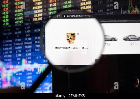 Logo de la société Porsche sur un site web avec des développements flous de la bourse en arrière-plan, vu sur un écran d'ordinateur à travers une loupe Banque D'Images