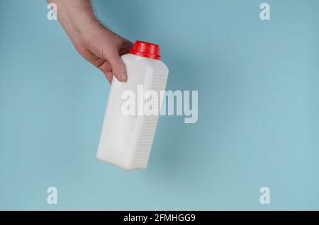 Poignées contenant blanc avec couvercle pour liquides sur fond bleu. Flacon générique rectangulaire en plastique avec couvercle rouge. Vue latérale. Banque D'Images