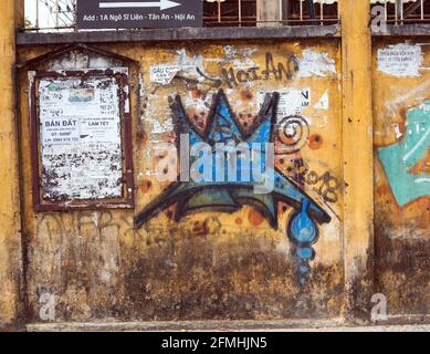 Avis publics et graffiti peint en aérosol sur le mur jaune à Hoi an, Vietnam Banque D'Images