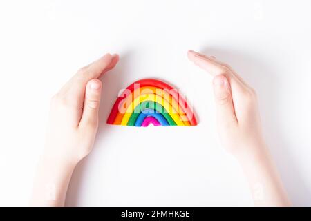 Les mains des enfants autour de la plasticine arc-en-ciel. Concept de famille LGBT. Vue de dessus. Couleurs du drapeau gay. Arrière-plan clair. Banque D'Images