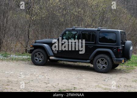 Une Jeep Wrangler Unlimited noire garée sur une route de gravier dans les montagnes Adirondack, dans la nature sauvage de New York au début du printemps Banque D'Images