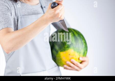 Une femme caucasienne se prépare à stab une pastèque à l'aide d'un couteau de cuisine aiguisé. Une image polyvalente pour les fruits d'été ainsi qu'une démonstration de for Banque D'Images