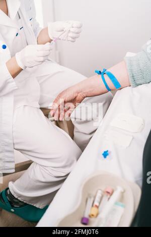 Du dessus de la récolte médique non reconnaissable en uniforme préparant le patient avec tourniquet pour la procédure intraveineuse à l'hôpital Banque D'Images