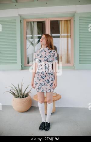 Pleine longueur belle jeune femme en été vêtements debout près maison contemporaine et vue Banque D'Images