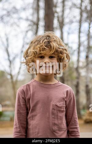 Enfant charmant en gris doux portant l'appareil photo allumé arrière-plan flou en plein air Banque D'Images