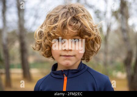 Charmant enfant dans les vêtements de sport vêtements porter regarder l'appareil photo allumé arrière-plan flou en plein air Banque D'Images