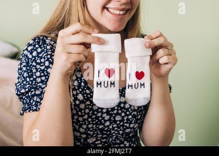 Rognez le contenu inreconnaissable expectant femme dans les vêtements d'ornement montrant des chaussettes Avec inscription I Mum et symbole coeur dans la maison Banque D'Images