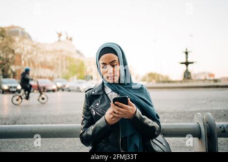 Femme musulmane en foulard sur la rue et la navigation téléphone portable Banque D'Images