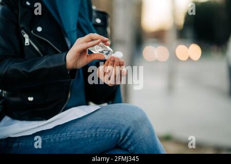 Récolte de la femme musulmane méconnaissable dans le hijab appliquant un désinfectant antibactérien sur mains dans la rue de la ville pendant la pandémie du coronavirus Banque D'Images