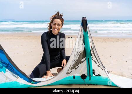 Femme kiter en combinaison d'installation de cerf-volant gonflable sur le sable ocean coast avec sac à dos et harnais sur le kitboard Banque D'Images