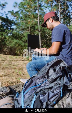 De dessous, nomad assis sur la pierre près des effets personnels et de l'utilisation netbook tout en travaillant à distance Banque D'Images