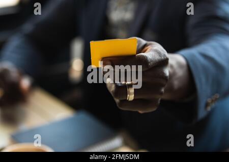 Petit homme d'affaires afro-américain méconnu avec carte de visite table de cafétéria pendant le petit déjeuner et regarder la caméra Banque D'Images