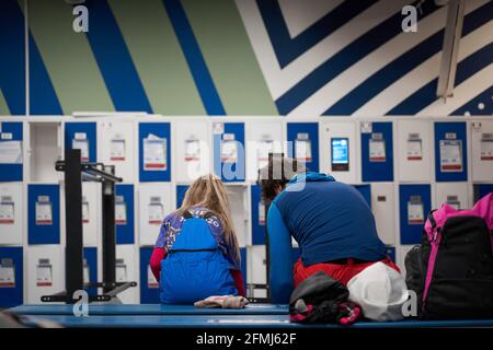 Vue arrière du père et de la fille anonymes assis sur le banc dans le vestiaire et pour le ski Banque D'Images