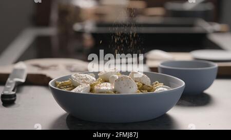 mozzarella au pesto penno dans un bol bleu sur un plan de travail en béton, photo large Banque D'Images