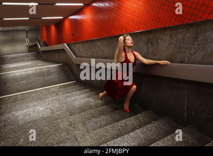 Nürnberg, U Bahn, Subway ou Metro in Nürnberg steht eine blonde junge Frau mit roten Kleid auf den Treppen zur Untergrundbahn Banque D'Images