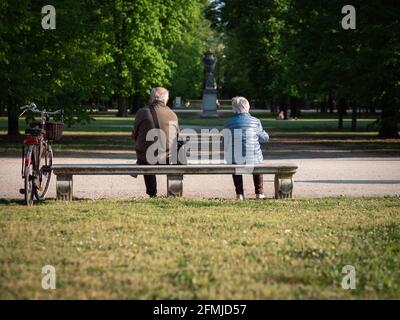 Un homme et une femme âgés assis loin à l'écart sur un banc dans un parc public. Banque D'Images