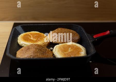 Le pain hamburger au sésame chauffe sur un gril. Processus de cuisson des hamburgers faits soi-même à la maison. Banque D'Images