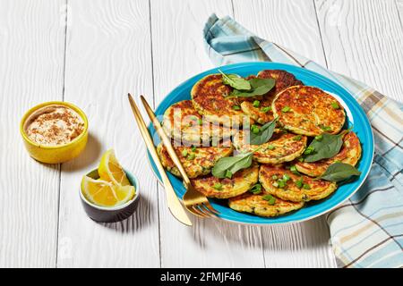 crêpes d'épinards aux pois chiches sur une assiette bleue sur un blanc table en bois avec houmous dans un petit bol Banque D'Images