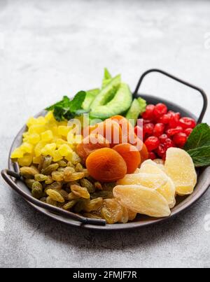 Plateau métallique avec différents types de fruits secs sur un fond en béton gris Banque D'Images