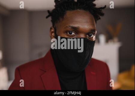 portrait d'un afro-américain dans un costume porte un masque médical noir Banque D'Images