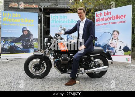 Solingen, Allemagne. 10 mai 2021. Hendrik Wüst (CDU), ministre des Transports de la Rhénanie-du-Nord-Westphalie, est assis devant des affiches de la campagne publicitaire "Je suis #leiserbiker" sur une moto. Sous le slogan 'I am #leiserbiker. Runter!Lärm runter!' Une initiative contre le bruit de la moto est lancée en NRW. 150 affiches à grande échelle sont prévues dans toute la Rhénanie-du-Nord-Westphalie. Credit: Oliver Berg/dpa/Alay Live News Banque D'Images