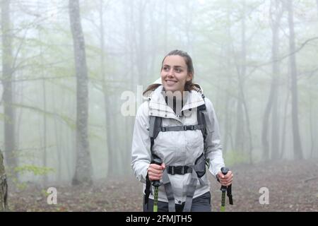 Vue de face d'un trekker heureux marchant dans un forêt brumeuse Banque D'Images