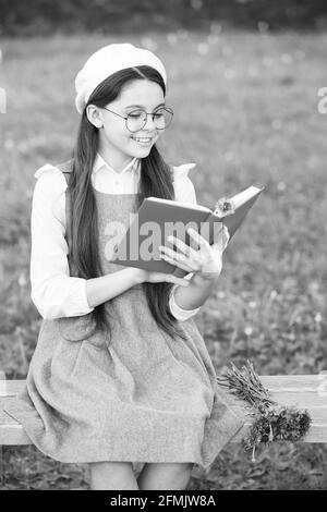 Élégante écolière enfant fille lisant le livre dans le parc, concept de langue française Banque D'Images