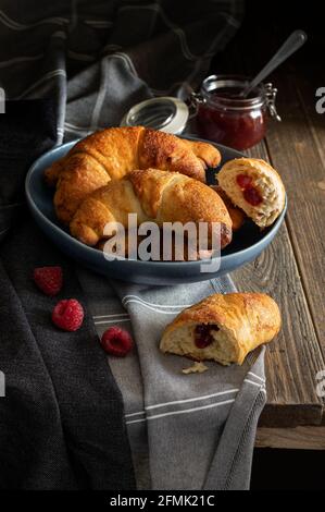 Petits pains faits maison fraîchement sortis du four remplis de confiture arrosée de sucre de ricin, servis sur un fond rustique sombre. Banque D'Images