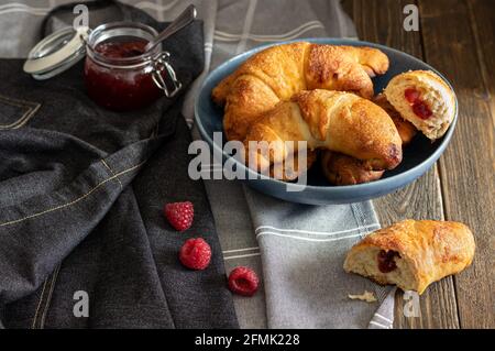 Petits pains faits maison fraîchement sortis du four remplis de confiture arrosée de sucre de ricin, servis sur un fond rustique sombre. Banque D'Images