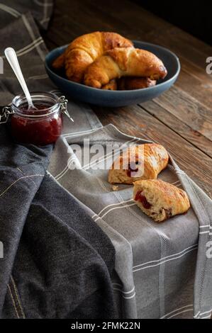 Petits pains faits maison fraîchement sortis du four remplis de confiture arrosée de sucre de ricin, servis sur un fond rustique sombre. Banque D'Images