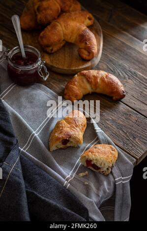 Petits pains faits maison fraîchement sortis du four remplis de confiture arrosée de sucre de ricin, servis sur un fond rustique sombre. Banque D'Images