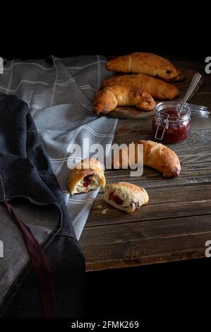 Petits pains faits maison fraîchement sortis du four remplis de confiture arrosée de sucre de ricin, servis sur un fond rustique sombre. Banque D'Images