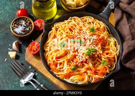 Pâtes traditionnelles italiennes à spaghetti faites maison avec sauce tomate, parmesan au fromage et basilic sur table en pierre sombre. Banque D'Images