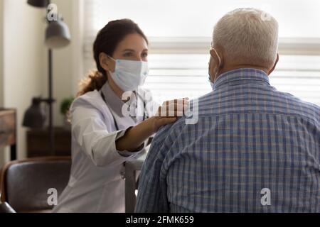 Une jeune femme empathique médecin tient la main sur l'épaule d'un patient âgé Banque D'Images